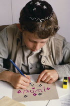 Boy at Sunday school wearing a kippah and making a card with Hebrew lettering.European Great Britain Kids Learning Lessons Northern Europe One individual Solo Lone Solitary Religion Religious Judaism...