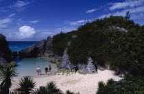 People in secluded cove with sand beach and seawater pool almost encircled by eroded rocks and vegetation.Beaches Bermudian Holidaymakers Resort Sandy Scenic Seaside Shore Tourism Tourist West Indies...
