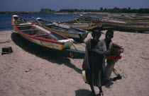 Two children on beach beside line of painted fishing boats pulled up onto the sand.2 African Beaches Kids Resort Sandy Seaside Senegalese Shore Tourism
