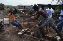 Using hand operated machine worked by the action of a lever to make bricks.leverage power force build building African Ghanaian Western Africa