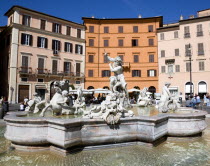 The Fountain of Neptune or Fontana del Nettuno in the Piazza Navona with tourists walking past restaurants beyondEuropean Italia Italian Roma Southern Europe Gray History Holidaymakers Religion Touri...