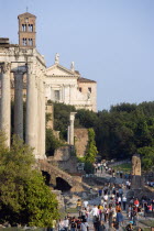 Tourists walking past the Temple of Antoninus and Faustina in the Forum with the belltower and facade of the church of Santa Francesca Romana beyondEuropean Italia Italian Roma Southern Europe Histor...