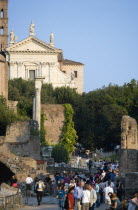 Tourists walking past the Temple of Antoninus and Faustina in the Forum with the facade of the church of Santa Francesca Romana beyondEuropean Italia Italian Roma Southern Europe History Holidaymaker...