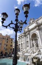 The 1762 Trevi Fountain by Nicola Salvi showing the central figure of the sea god Neptune with tourists in the Piazza Di Trevi and an ornate lamppost in the foregroundEuropean Italia Italian Roma Sou...