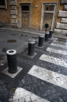 Automatic rising bollards and a pedestrian crossing in a side street with red and green traffic control lightsEuropean Italia Italian Roma Southern Europe Gray Grey