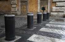 Automatic rising bollards and a pedestrian crossing in a side street with red and green traffic control lightsEuropean Italia Italian Roma Southern Europe Gray Grey