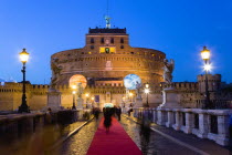 ITALY, Rome, Lazio, The fortress of Castel Sant Angelo illuminated at night with a red carpet laid across the bridge of Ponte Sant Angelo for an evening reception.