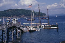 Wooden jetty with yacht moored at side  various boats on water and tree covered headland beyond.American Inn New England North America Pub Tavern United States of America Great Britain Northern North...