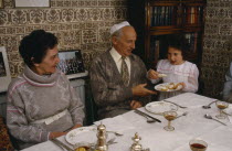 Jewish New Year meal  young girl passing the chala or bread to family members.European Great Britain Immature Kids Northern Europe Old Senior Aged Religion Religion Religious Judaism Jew Jews UK Unit...