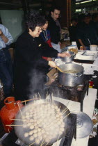 Women cooking on street stall during New Year celebrations in Chinatown.Chinese communitysociety ethnic racial diversity Asian European Female Woman Girl Lady Great Britain Londres Northern Europe U...