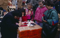 Calligraphist writing Western names in Chinese during New Year celebrations in Chinatown.  Sign beside stall reads  East Meets West .calligraphy Chinese communitysociety ethnic racial diversity Asia...