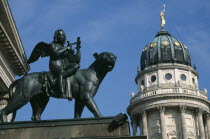 Gendarmenmarkt.  Bronze statue of winged  lute playing Bacchus riding a panther in front of the Schauspielhaus with domed roof of the Franzosischer Dom behind.Konzerthaus Concert Hall French Cathedra...