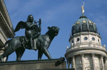 Gendarmenmarkt.  Bronze statue of winged  lute playing Bacchus riding a panther in front of the Schauspielhaus with domed roof of the Franzosischer Dom behind.Konzerthaus Concert Hall French Cathedra...