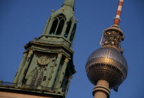 Angled detail of the Fernsehturm or television tower beside clock and bell tower of historic St Mary s Church also called Marienkirche.juxtaposition  religious secular Deutschland European History Re...
