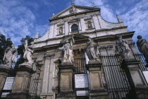 Exterior facade of Church of Saints Peter and Paul with  statues of the twelve disciples and religious iconography and sign detailing times of Mass services on ironwork gate.12 apostles Eastern Europ...