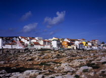 Peniche. Atlantic Ocean town. View across low cliffs and rocky foreshore towards colourful painted houses with red tiled roofs on the south side of the town European Scenic Southern Europe Portugese...