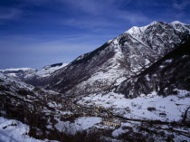 Pyrenees. Elevated view north east from the route to Col du Portillon over snow covered valley looking over the rooftops of the town of Ville Bossost. The mountain Montlude 2518 metres 8246 feet and t...