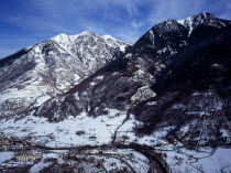 Pyrenees. Elevated view north east from the route to Col du Portillon looking over the rooftops of  the town of Ville Bossot. Snow covered mountains including Montlude 2518 metres 8246 feet and Montan...