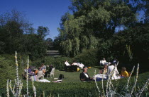 Opera attendees enjoying picnics in the gardens during Opera interval.Picnicking European Great Britain Northern Europe Performance UK United Kingdom British Isles Public Presentation