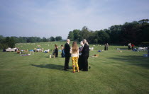 Opera attendees enjoying picnics in the gardens during performance intervalEuropean Great Britain Northern Europe Public Presentation UK United Kingdom British Isles