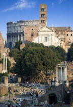 View of The Forum with the Colosseum rising behind the bell tower of the church of Santa Francesca Romana with tourists and the Temple of The Vestals in the foregroundEuropean Italia Italian Roma Sou...