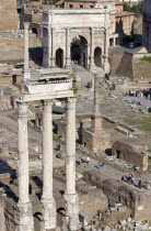 The three remaining Corinthian columns of the Temple of Castor and Pollux with the triumphal Arch of Septimius Severus in the Forum with tourists walking around the ruinsEuropean Italia Italian Roma...