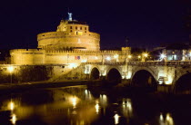 Castel Sant Angelo illuminated at night with tourists on the Ponte Sant Angelo bridge over the River Tiber lined with statues of winged angelsEuropean Italia Italian Roma Southern Europe History Holi...