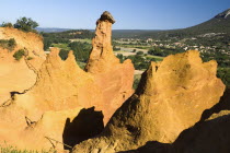 Colorado Provencal.  Cheminee de Fee or Fairy Chimneys.  Early morning light on smooth  eroded  ochre rocks with village of Rustrel in the distance beyond.Ochre Trail European French Western Europe S...