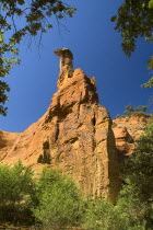 Colorado Provencal.  Cheminee de Fee or Fairy Chimneys.  View towards capped  eroded ochre rock pinnacle framed by trees.Ochre Trail European French Western Europe Scenic