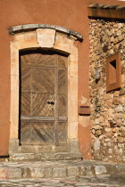 Roussillon.  Old  wooden door with stone surround set into ochre coloured exterior wall of building.European French Western Europe Colored