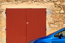 Roussillon.  Part view of blue car parked outside town building of red stone with red painted double doorway.European French Western Europe 1 Automobile Automotive Cars Motorcar Single unitary Automo...