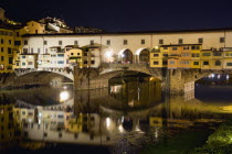 The 14th century Ponte Vecchio or Old Bridge across the River Arno illuminated at night with sightseers on the bridgeEuropean Italia Italian Southern Europe Toscana Tuscan Firenze History Holidaymake...