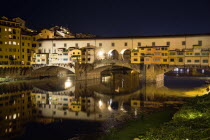 The 14th century Ponte Vecchio or Old Bridge across the River Arno illuminated at night with sightseers on the bridgeEuropean Italia Italian Southern Europe Toscana Tuscan Firenze History Holidaymake...