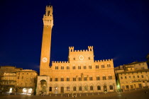 The Torre del Mangia campanile belltower and facade of the Palazzo Publico town hall in the Piazza del Campo and surrounding buildings illuminated at nightEuropean Italia Italian Southern Europe Tosc...