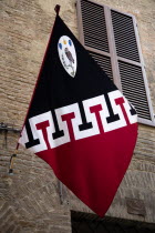 Palio flag of the Contrada of the Owl or Civetta hanging from a wall on a flagpost in a sidestreetEuropean Italia Italian Southern Europe Toscana Tuscan History