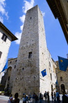 Tourists in Via di Querececchio below one of the town medieval towers under a blue skyEuropean Italia Italian Southern Europe Toscana Tuscan 1 Gray History Holidaymakers Single unitary Tourism