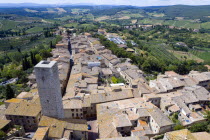View across the rooftops past one of the towers of the medieval town towards the Tuscan countryside of farmlandEuropean Italia Italian Southern Europe Toscana Tuscan 1 Farming Agraian Agricultural Gr...