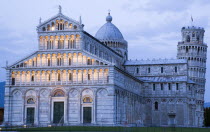 Campo dei Miracoli or Field of Miracles The Duomo Cathedral and Leaning Tower belltower or Torre Pendente illumunated at dusk with tourist walking at their baseEuropean Italia Italian Southern Europe...