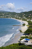 Waves breaking on the long stretch of Grand Anse Beach with people in the surf and on the beach with the inland hills in the distanceScenic West Indies Beaches Caribbean Grenadian Greneda Holidaymake...