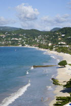 Waves breaking on the long stretch of Grand Anse Beach with people in the surf and on the beach with the inland hills in the distanceScenic West Indies Beaches Caribbean Grenadian Greneda Holidaymake...