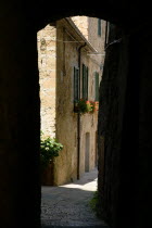 Val D Orcia View through a narrow alley to stone houses with red geraniums in window boxesEuropean Italia Italian Southern Europe Toscana Tuscan