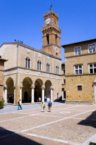 Val D Orcia Piazza Pio II with Palazzo Communale Town Hall with its campanile belltower and Palazzo Borgia on the right. Tourists walking in the square under a blue skyEuropean Italia Italian Souther...
