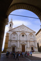 Val D Orcia The Duomo in Piazza Pio II seen through an arch with tourists walking in the square. Built in 1459 by the architect Rossellino for Pope Pius IIEuropean Italia Italian Southern Europe Tosc...