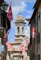 Red and white flags of the Castello Quartieri or quarter decorate a narrow street of the medieval town leading to the belltower of the Collegiata Collegiate Church of the Saints Quirico and GiulittaE...