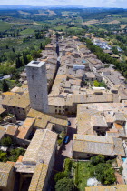 View across the rooftops past one of the towers of the medieval town towards the Tuscan countryside of farmlandEuropean Italia Italian Southern Europe Toscana Tuscan 1 Farming Agraian Agricultural Gr...