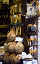 Shop display of wild boar products including salami proscuito and full cured legs with a stuffed wild boar head on the wallEuropean Italia Italian Southern Europe Toscana Tuscan History Store