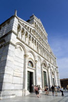 The Campo dei Miracoli or Field of Miracles.The Lombard style 12th Century facade of the Duomo Cathedral with tourists walking in front at the base under a blue skyEuropean Italia Italian Southern Eu...