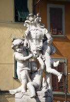 A statue of three Cherubs holding the heraldic symbol of Pisa in The Campo dei Miracoli or Field of MiraclesEuropean Italia Italian Southern Europe Toscana Tuscan 3 Gray