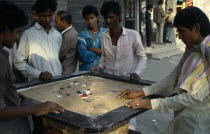 Young men playing board game with counters in street.Asia Asian Bangladeshi Dacca Immature Male Man Guy  Asia Asian Bangladeshi Dacca Immature Male Man Guy
