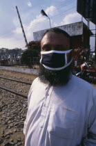 Bearded man wearing a mask covering his mouth and nose against air pollutionAsia Asian Bangladeshi Dacca Ecology Entorno Environmental Environnement Green Issues Male Men Guy One individual Solo Lone...